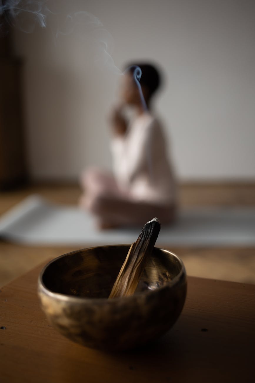 burning incense and a woman practising yoga in the background