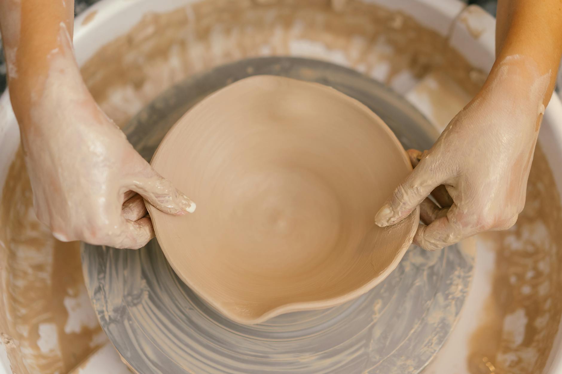 woman shaping a clay bowl on a potters lathe